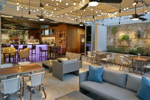 un restaurante con mesas y sillas y un bar en The Sarasota Modern, a Tribute Portfolio Hotel en Sarasota