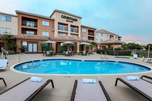 a pool in front of a hotel with tables and chairs at Courtyard by Marriott Orlando Lake Mary North in Lake Mary