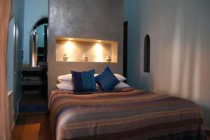 1 dormitorio con 1 cama con almohadas azules y blancas en Riad is entire house for sole occupancy up to 6 adults & 2 children, en Marrakech