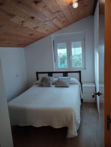 1 dormitorio con 1 cama blanca y 2 almohadas en CASITA INDEPENDIENTE EN SUANCES Parking - Wifi - Jardín, en Cortiguera