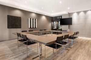AC Hotel Ponferrada by Marriott في بونفيراذا: قاعة اجتماعات مع طاولة وكراسي خشبية كبيرة
