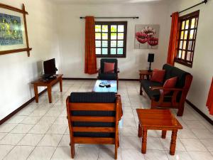 sala de estar con sofá, sillas y TV en Sunset Cove Villa, en Grand'Anse Praslin