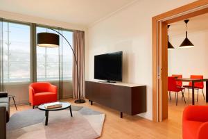 a living room with a television and red chairs at Lyon Marriott Hotel Cité Internationale in Lyon