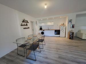 een keuken en een woonkamer met een glazen tafel en stoelen bij Bas de villa proche Ajaccio in Bastelicaccia