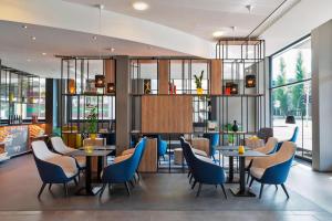 a restaurant with blue chairs and tables and windows at Courtyard by Marriott Zurich North in Zurich
