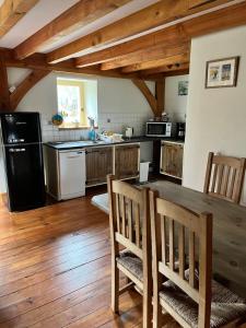 uma cozinha com uma mesa de madeira e um frigorífico preto em Chez Jallot - Upper Gite em Vidaillat