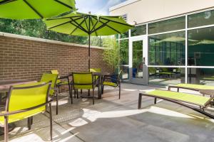 patio ze stołami i krzesłami z zielonymi parasolami w obiekcie SpringHill Suites by Marriott Raleigh Apex w mieście Apex