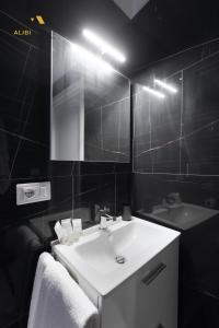 a bathroom with a white sink and a mirror at [ALIBI SUITES] Suite MUSEUM: Gioiello con Vista sul Museo Archeologico Nazionale, Letto e Doccia con Cromoterapia, Smart tv, WiFi e A/C in Ruvo di Puglia