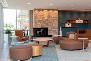 Fairfield Inn & Suites by Marriott Indianapolis Carmel في كارميل: لوبي يحتوي على موقد حجري واريكة وكراسي