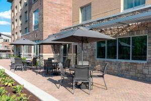 un patio avec des tables, des chaises et des parasols en face d'un bâtiment dans l'établissement Fairfield Inn & Suites by Marriott Indianapolis Carmel, à Carmel