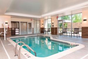 une grande piscine avec des chaises et une table dans l'établissement Fairfield Inn & Suites by Marriott Indianapolis Carmel, à Carmel