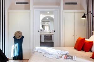 a bedroom with a bed with orange pillows and a bathroom at Samaritana Suites in Palma de Mallorca