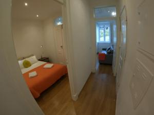 a small bedroom with an orange bed and a hallway at Lisbon, renewed T1 apartment with pateo near Martires da Patria in Lisbon