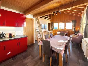 uma cozinha e sala de jantar com mesa e armários vermelhos em Zigzag on the slopes em Anzère