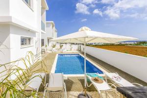 a villa with a swimming pool and an umbrella at Villa Alasia in Paralimni