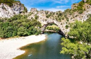 a bridge over a river next to a beach at Le Mas du Berger in Saint-Quentin-la-Poterie