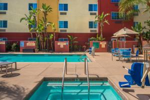 a swimming pool in a hotel with chairs and a building at TownePlace Suites by Marriott Anaheim Maingate Near Angel Stadium in Anaheim