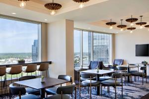 un ristorante con tavoli, sedie e ampie finestre di JW Marriott Grand Rapids a Grand Rapids