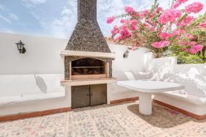 a fireplace on a patio with a bench and flowers at Chalet Umbelina con jardin y vista al mar in Palm-mar
