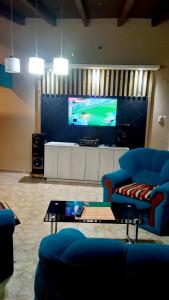 sala de estar con 2 sillas azules y TV en Casa de campo en Belén