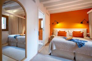a bedroom with an orange wall and a large mirror at Samaritana Suites in Palma de Mallorca