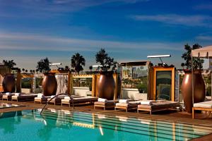 a hotel swimming pool with lounge chairs next to a pool at SLS Hotel, a Luxury Collection Hotel, Beverly Hills in Los Angeles