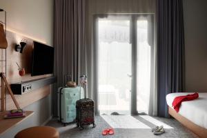 a hotel room with a suitcase and a sliding glass door at Moxy Sophia Antipolis in Biot