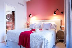 a bedroom with a white bed with a red wall at Samaritana Suites in Palma de Mallorca