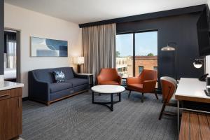 a living room with a couch and a table and chairs at Courtyard by Marriott Owatonna Downtown in Owatonna