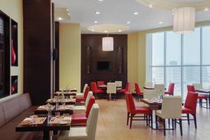 a dining room with tables and red chairs at Courtyard by Marriott Jazan in Jazan