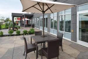 a table and chairs with an umbrella on a patio at Courtyard by Marriott Saskatoon Airport in Saskatoon