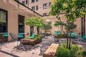 an outdoor patio with chairs and tables and trees at Aloft München in Munich