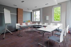 une salle de conférence avec des tables et des chaises et un tableau blanc dans l'établissement Aloft München, à Munich