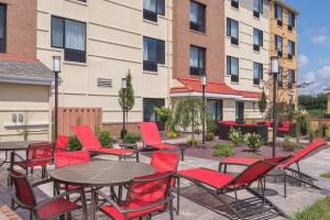 a group of red chairs and tables in front of a building at TownePlace Suites by Marriott New Hartford in New Hartford