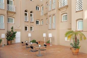 une cour avec des tables et des chaises dans un bâtiment dans l'établissement AC Hotel La Línea by Marriott, à La Línea de la Concepción