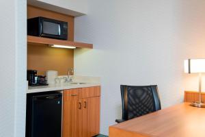 una pequeña cocina con mesa y nevera negra en SpringHill Suites by Marriott Peoria, en Peoria