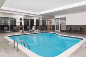 una grande piscina in un hotel con tavoli e sedie di Fairfield Inn & Suites by Marriott Raleigh Wake Forest a Wake Forest