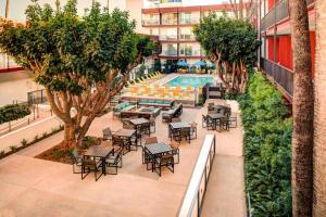 an outdoor patio with tables and chairs and a swimming pool at Fairfield Inn & Suites by Marriott Los Angeles LAX/El Segundo in El Segundo