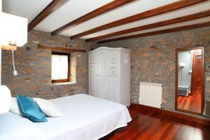 1 dormitorio con cama blanca y pared de piedra en Casa Rural Haitzetxea, en Zugarramurdi