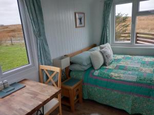 a bedroom with a bed and a table and a window at Hillside Camping Pods and Shepherd's Hut in Wick