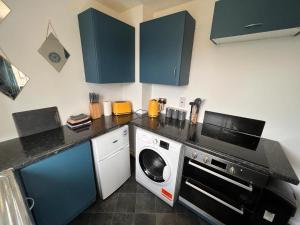 a kitchen with a washing machine and a microwave at Spacious Apartment with Parking in Norwich