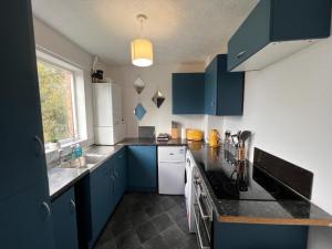 a kitchen with blue cabinets and a black counter top at Spacious Apartment with Parking in Norwich