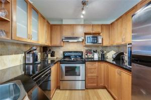 uma cozinha com armários de madeira e electrodomésticos de aço inoxidável em Stampede Park em Calgary