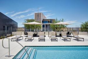 una piscina con sillas y sombrillas en un edificio en AC Hotel by Marriott Phoenix Tempe/Downtown, en Tempe