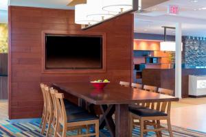 Fairfield Inn & Suites by Marriott Indianapolis Fishers في فِشرز: غرفة طعام مع طاولة وكراسي وتلفزيون