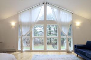 - une grande fenêtre avec des rideaux blancs dans la chambre dans l'établissement Woodland Hills Modern Cottage Minutes from Downtown Great Barrington, à Great Barrington