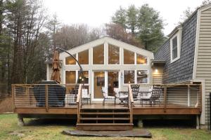 a screened in porch with chairs and tables on a house at Woodland Hills Modern Cottage Minutes from Downtown Great Barrington in Great Barrington