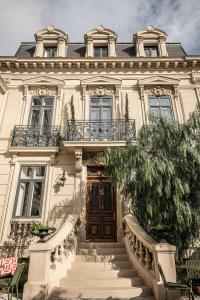 une grande maison blanche avec des escaliers menant à une porte. dans l'établissement Hôtel Le Mosaïque, à Narbonne