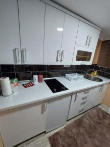 a white kitchen with white cabinets and a sink at Stan na Dan Jovanovic in Valjevo