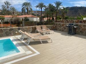 een patio met 2 ligstoelen en een zwembad bij Casa Tauro Gran Canaria in Mogán